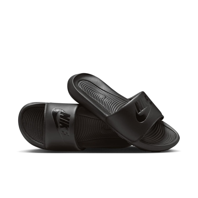 Black slide sandal side view with molded strap and ribbed footbed texture.