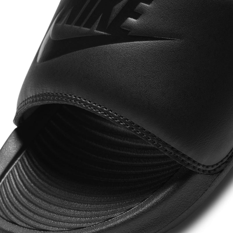 Close-up of black slide sandal strap and footbed with ridged texture and stitching.