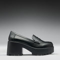Black platform loafer shoe on a gray background