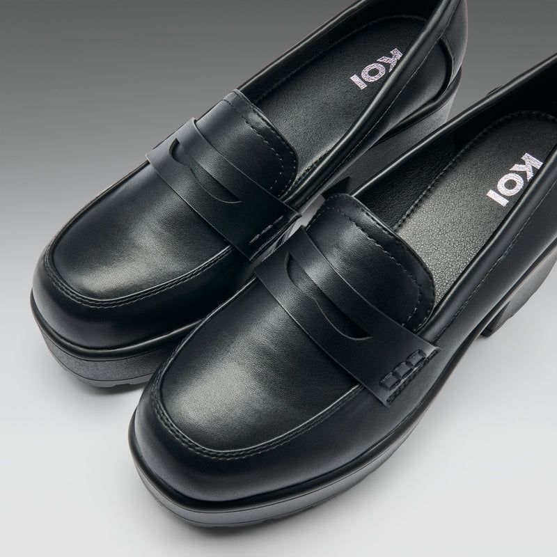 Black loafers with 'Koi' branding on a gray background