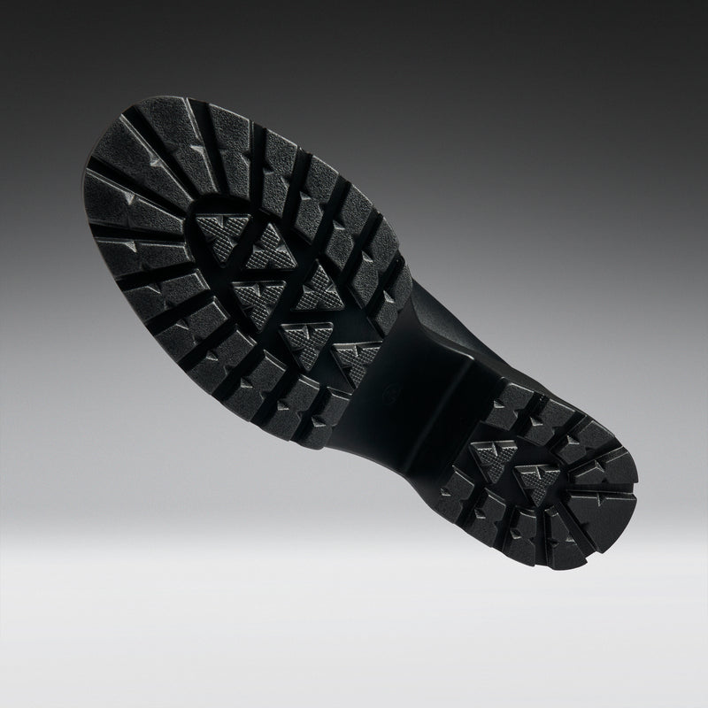 Close-up of a black boot sole with tread pattern on a gradient background