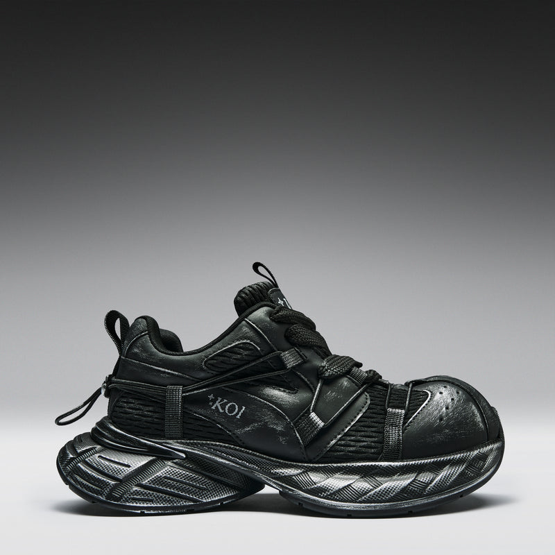 Black sneaker with a brand logo on a gray background