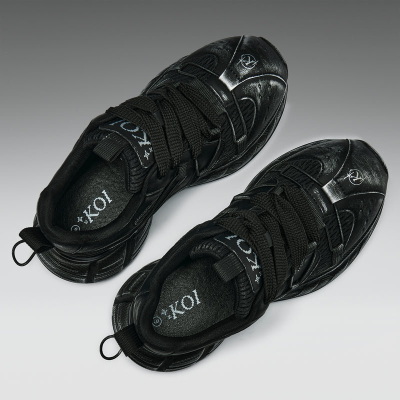 Pair of black sneakers with 'KOI' branding on a light gray background