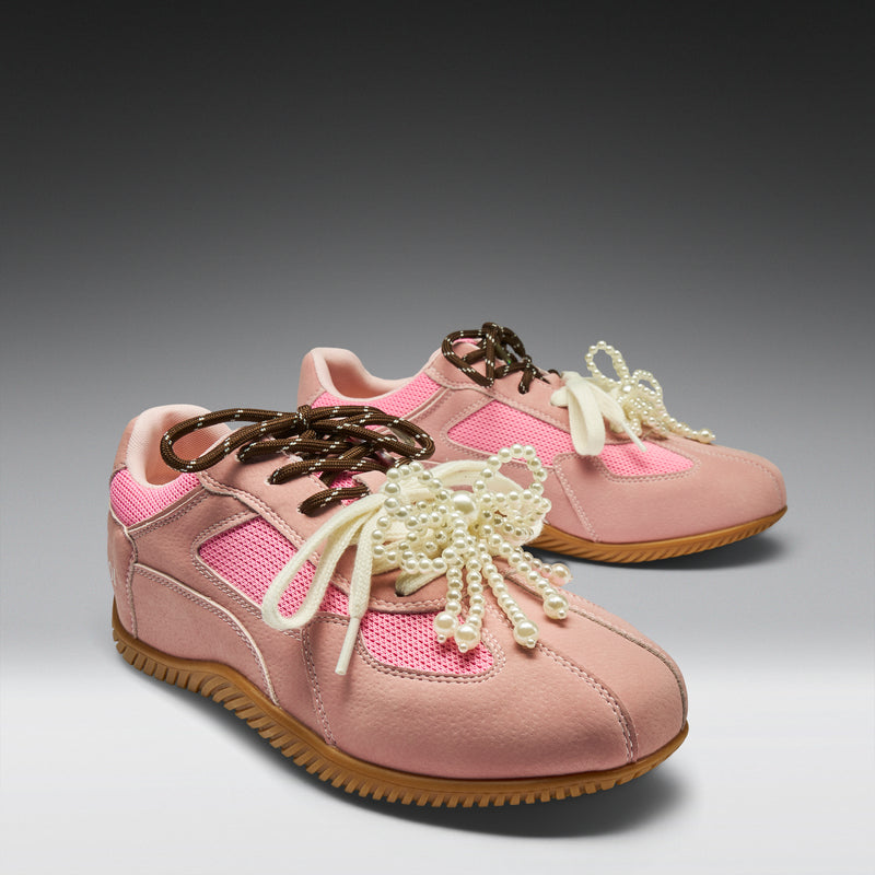 Pair of pink sneakers with decorative laces on a gray background