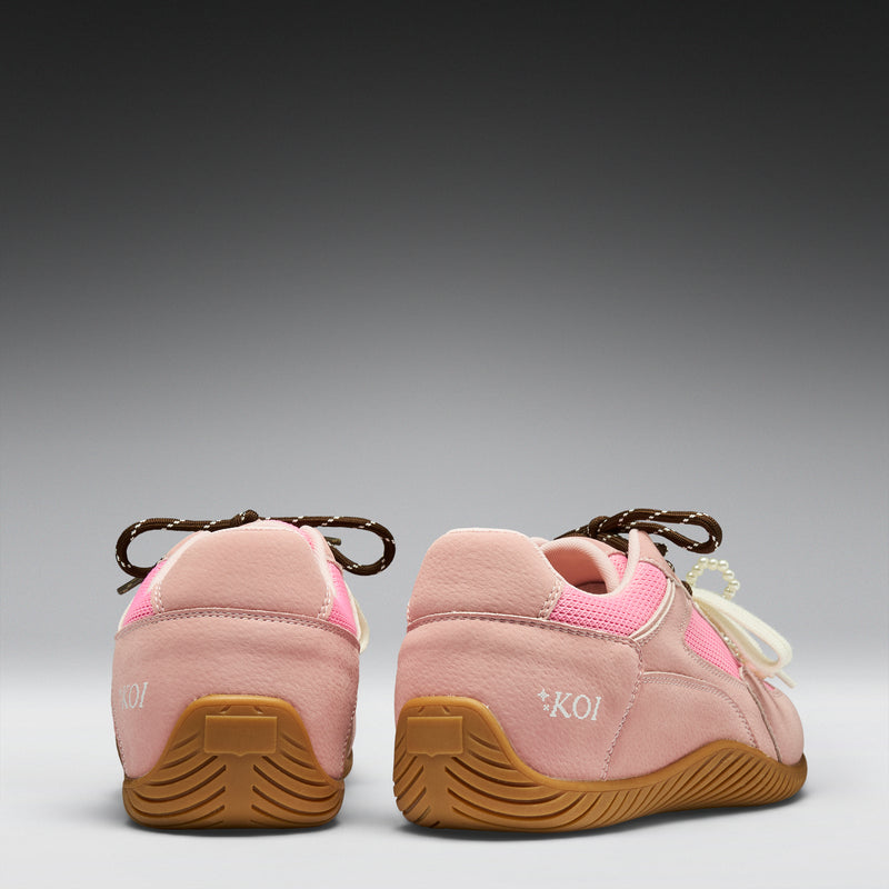 Pair of pink shoes with brown soles on a gray background