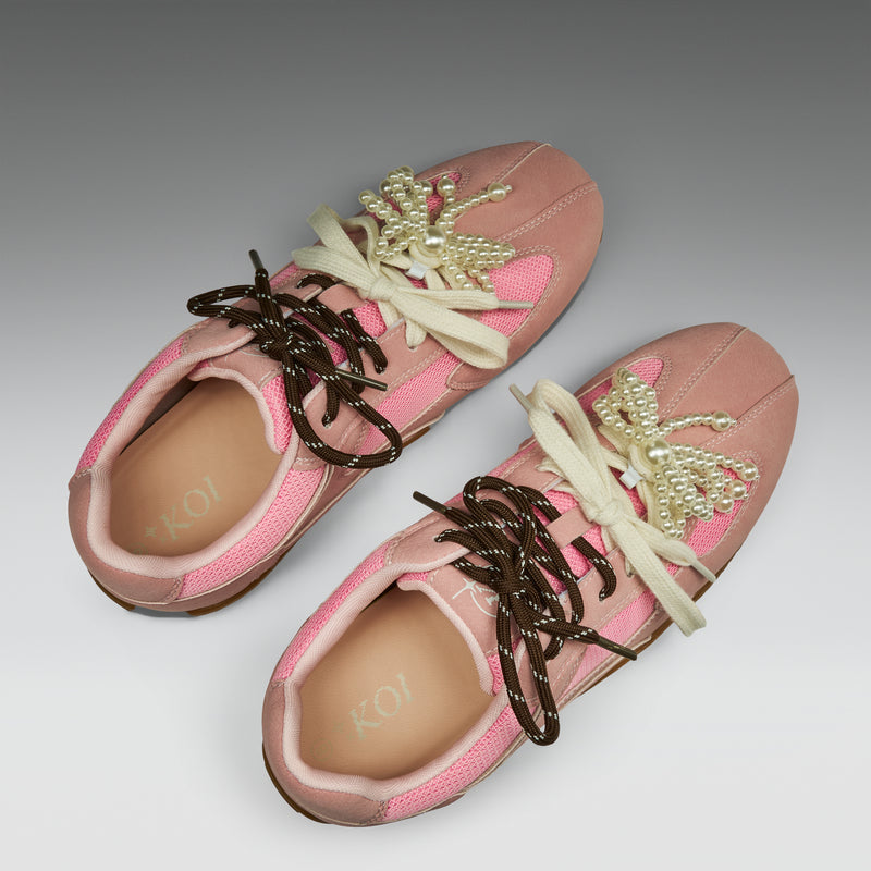 Pink sneakers with decorative elements on a gray background