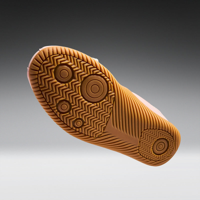 Close-up of a brown shoe sole with tread pattern on a gray background