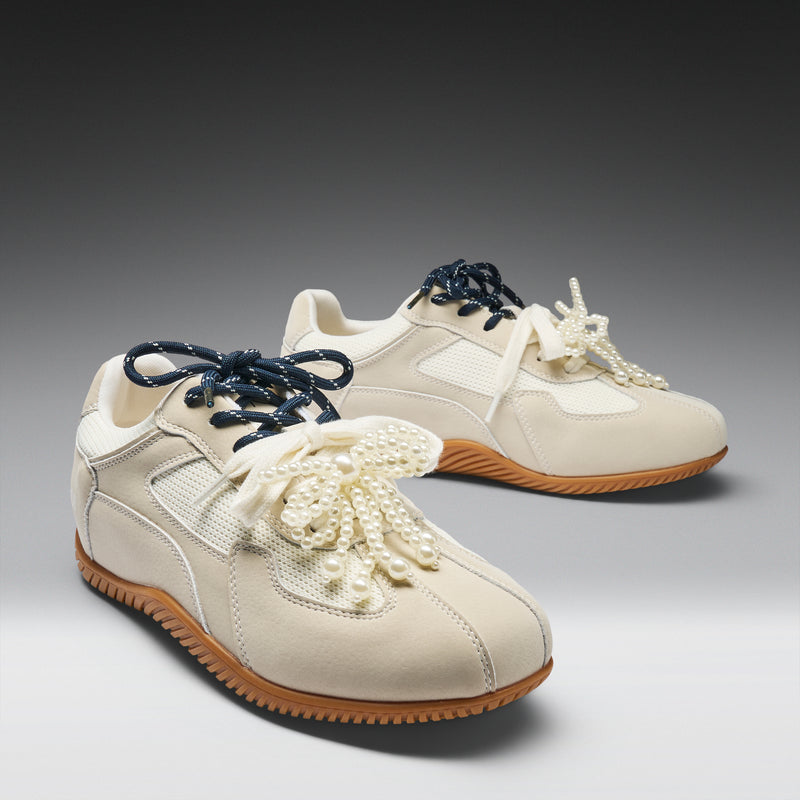 Pair of cream-colored sneakers with decorative flowers on a gray background