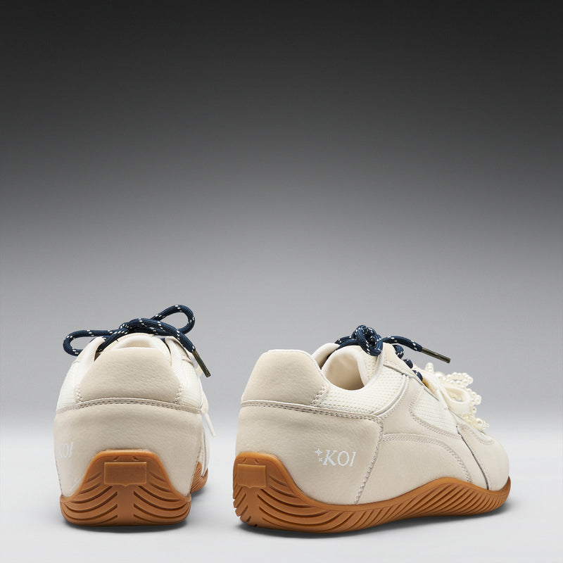 Pair of white sneakers with brown soles on a gray background