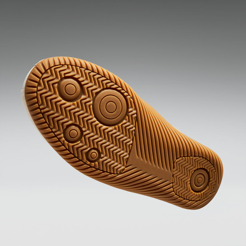 Close-up of a brown shoe sole with tread pattern on a gray background