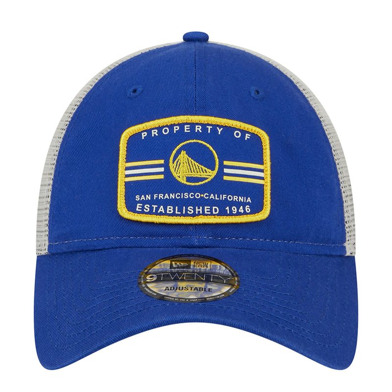 Blue trucker cap with front “Property of” patch and gold crest; adjustable strap.