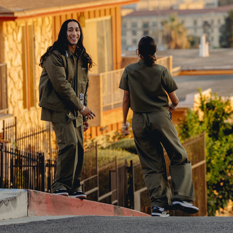 Women’s wide-leg military green pants with pockets and belt loops, rear walking view.
