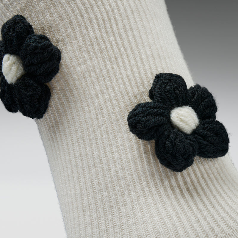 Close-up of a beige knitted garment with black flower-shaped buttons.