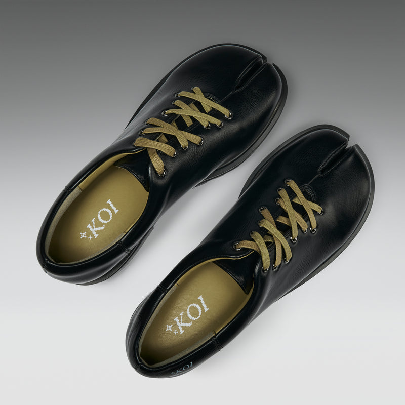 Pair of black shoes with yellow laces on a light gray background