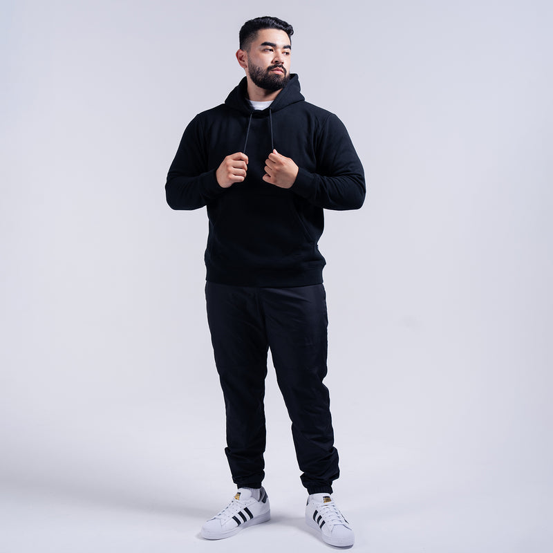 Black wind pants on model, elastic cuffs and tapered fit