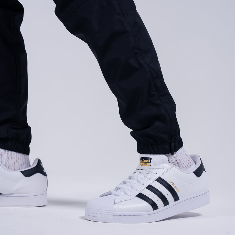 Black tapered wind pants with elastic ankle cuffs