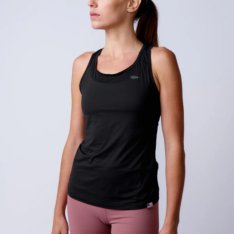 Woman wearing GORUCK black athletic tank top and pink leggings in studio setting