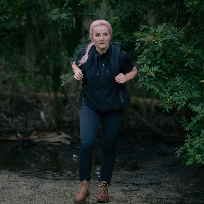 Woman wearing GORUCK black Tough Dry fleece vest, hiking outdoors with backpack in forest