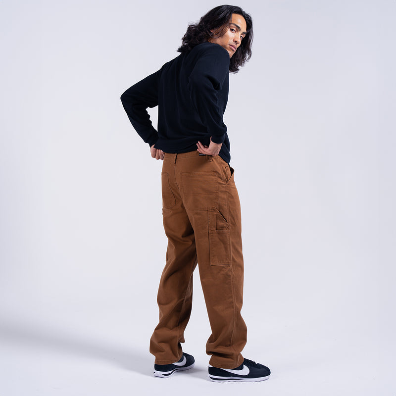 Men's brown work pants on model, back view with patch pocket details