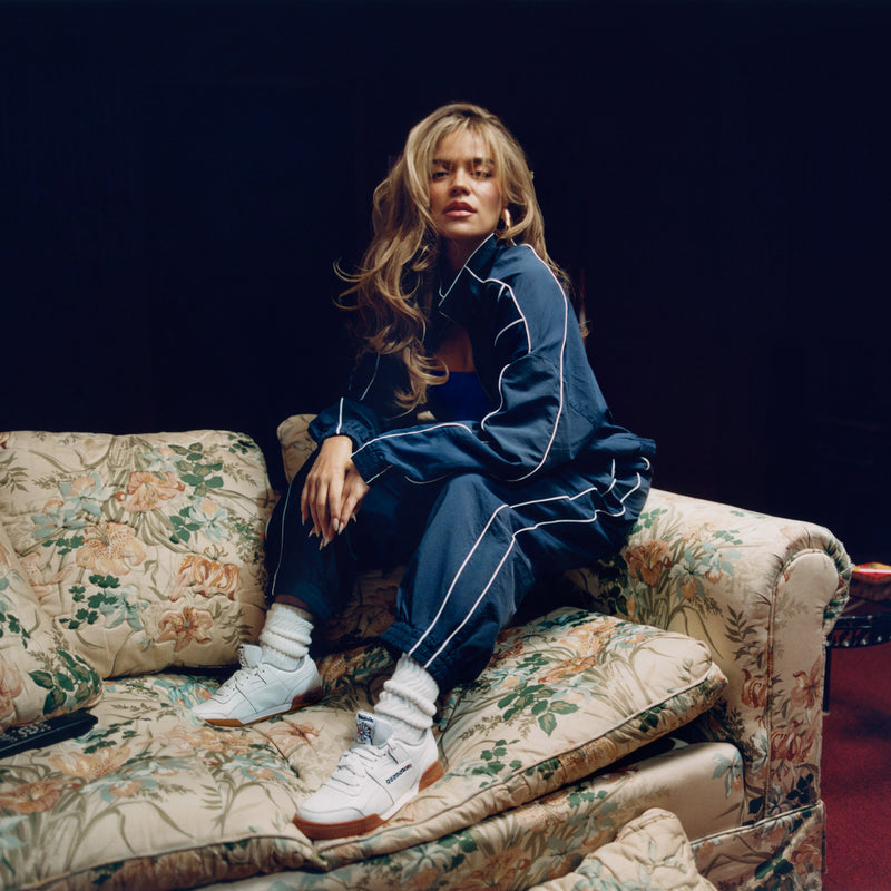 Women’s Reebok sneakers on model’s feet: white uppers with orange gum soles